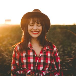 woman smiling in field with sunbeam behind her